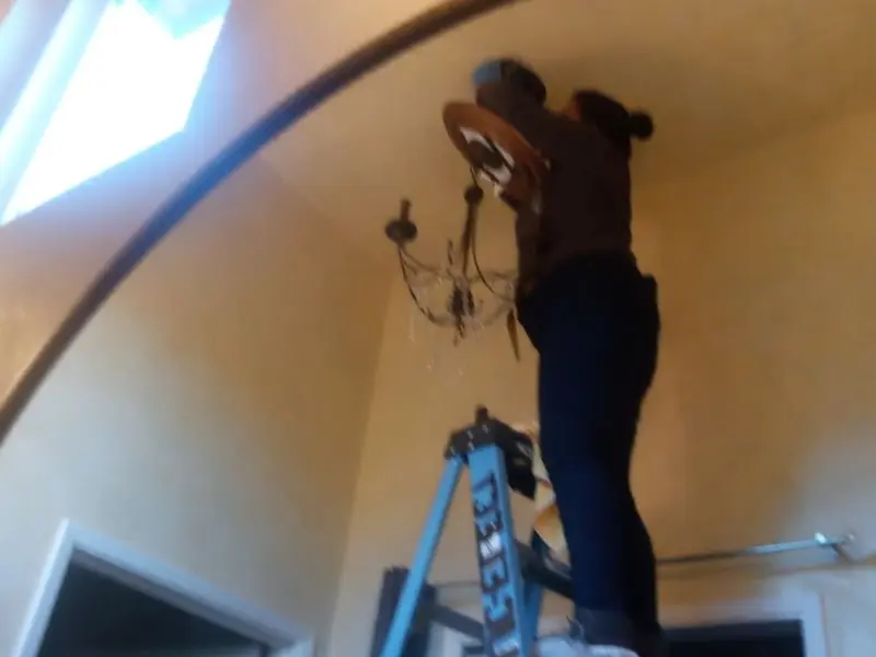 Electrician installing a chandelier in a University Park residence